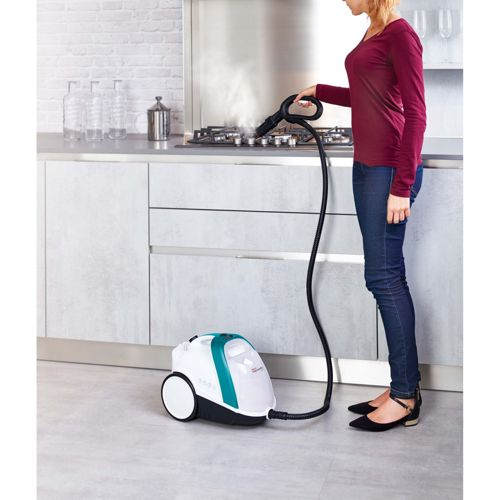 Una donna pulisce un fornello a gas in cucina con un pulitore a vapore.