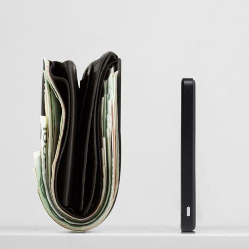 Un portefeuille noir rempli d'argent à côté d'un objet noir fin.