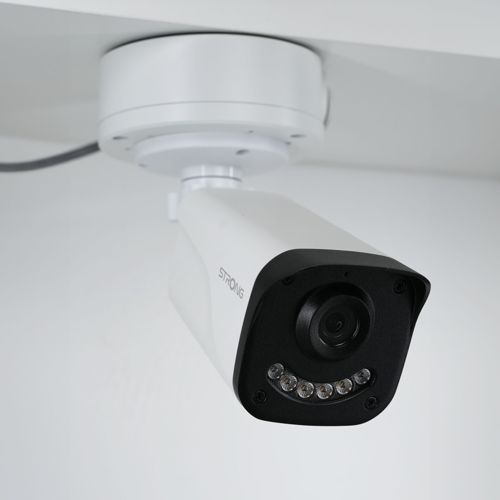Una telecamera di sicurezza bianca con frontale nero e LED è montata sul soffitto.