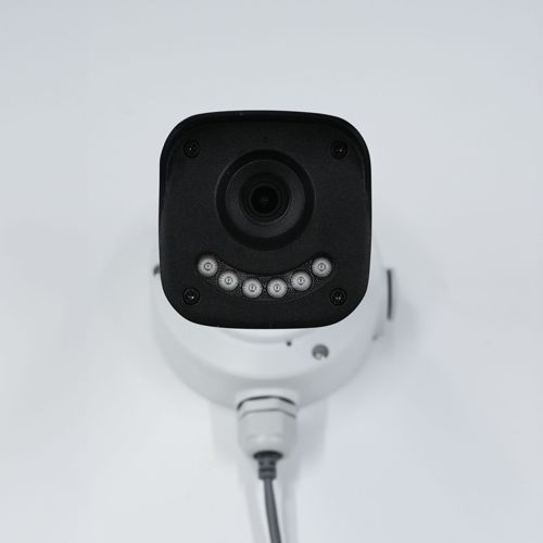 Telecamera di sicurezza nera con lente e LED, montata su superficie bianca.