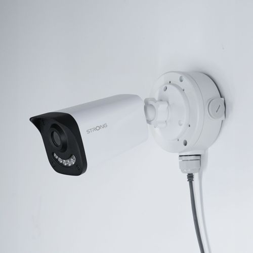 Una telecamera di sicurezza bianca con frontale nero è montata a parete.