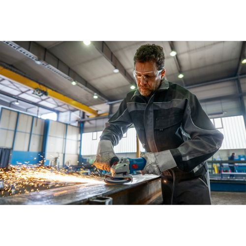 Ein Mann mit Schutzbrille schleift Metall, Funken fliegen.