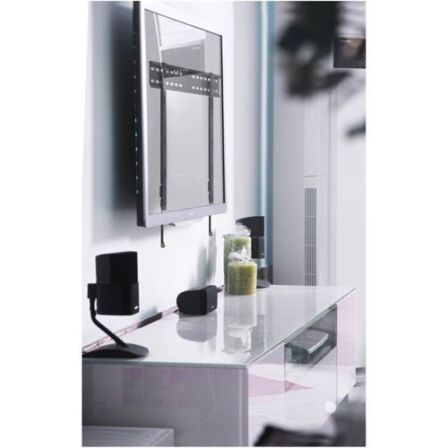 Een moderne tv aan de muur boven een tv-meubel met glazen blad en luidsprekers.