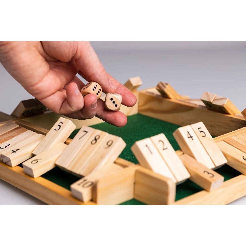 Una mano tiene due dadi sopra un tabellone di gioco con alette numerate in legno.