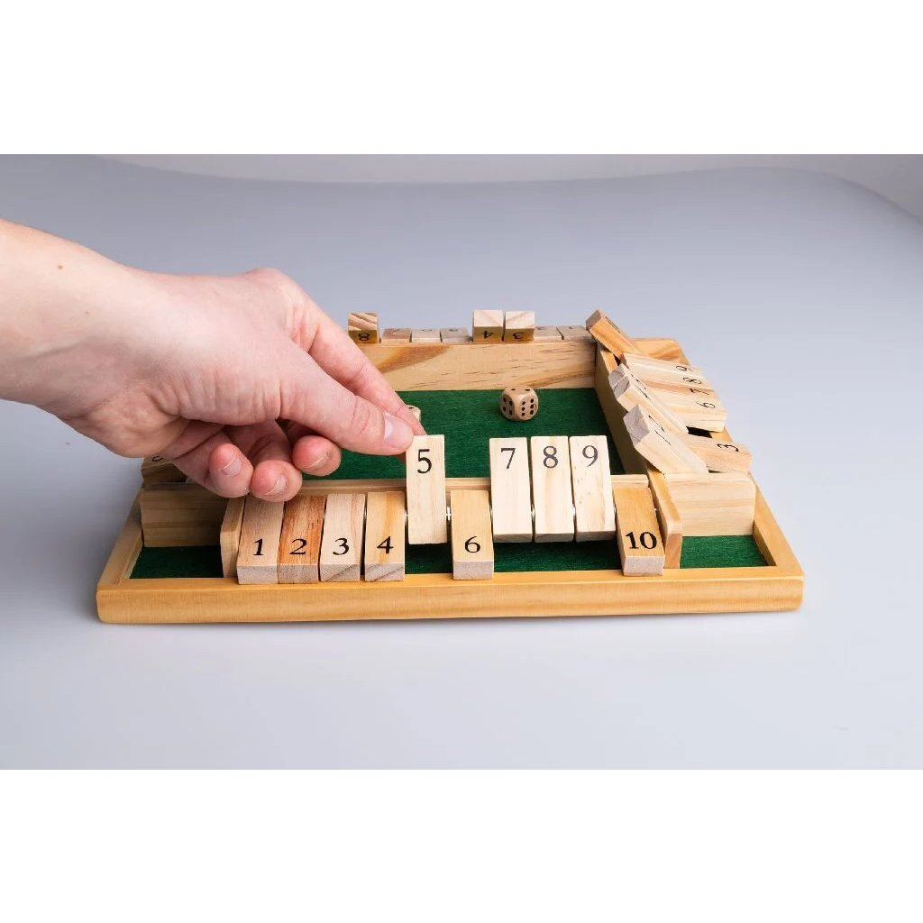Una mano gioca a un gioco di dadi in legno con tessere numerate.