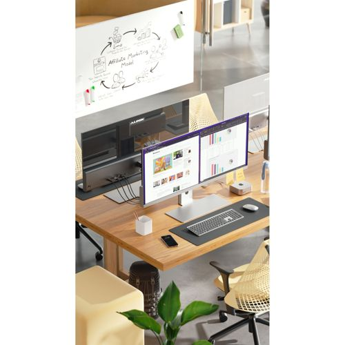 Una scrivania con doppio monitor, tastiera, mouse e lavagna con diagrammi.