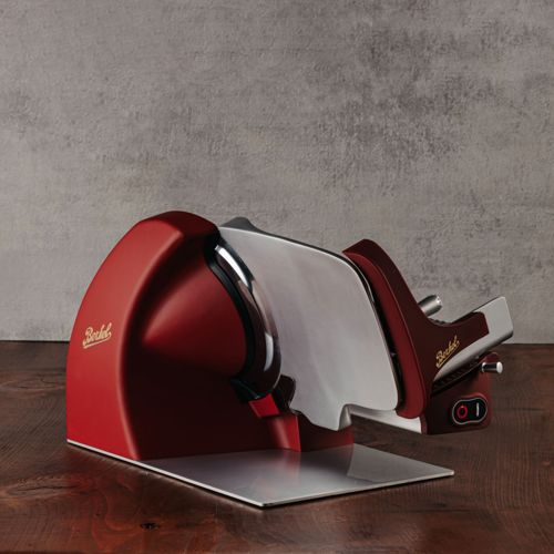 Ein roter Berkel Fleischschneider mit glänzender Klinge steht auf einem Holztisch.