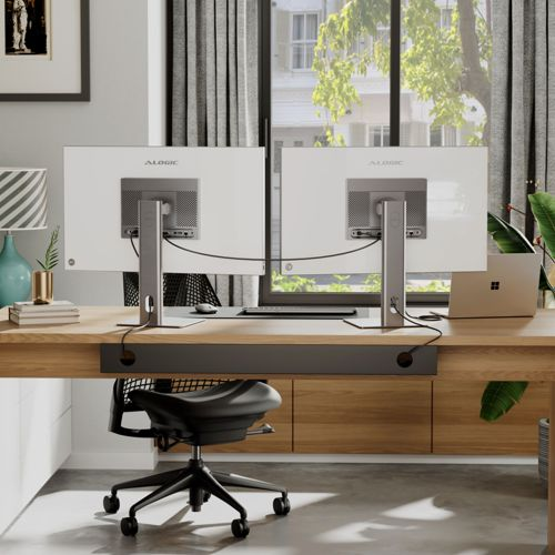 Deux écrans d'ordinateur sur un bureau en bois, avec un ordinateur portable et une chaise.