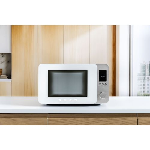 Un microondas SMEG blanco con controles plateados se sienta en una encimera.