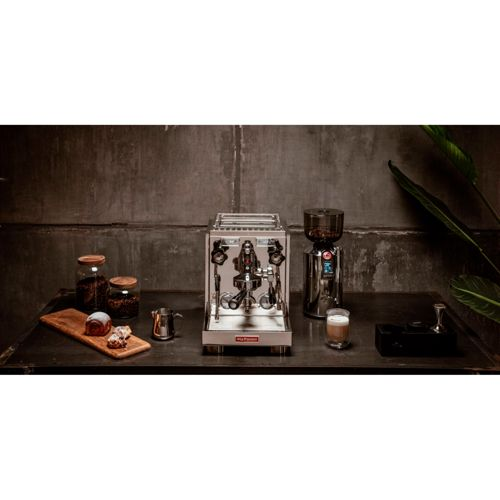 Eine glänzende Espressomaschine und Mühle mit Kaffeebohnen, Gebäck und einem Latte.