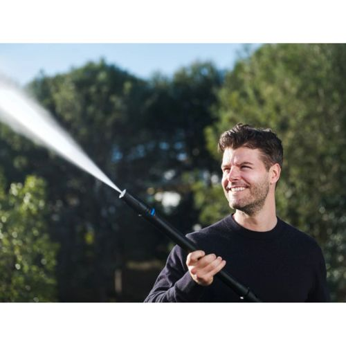 Un uomo che tiene un'idropulitrice all'aperto, l'acqua spruzza dall'ugello.