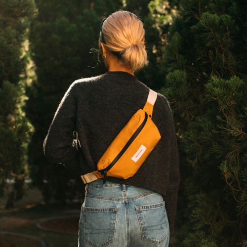 Donna con marsupio giallo davanti agli alberi