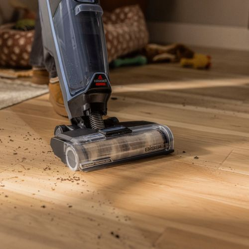 Un aspirapolvere pulisce lo sporco da un pavimento in legno. Primo piano.