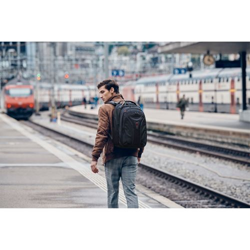 Un homme avec un sac à dos se tient sur le quai, un train part.