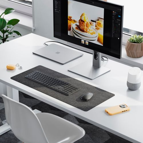 Una scrivania con monitor, laptop, tastiera, mouse e telefono.