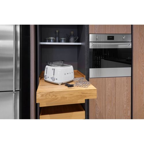Una tostadora SMEG blanca está en un estante extraíble de madera en una cocina.
