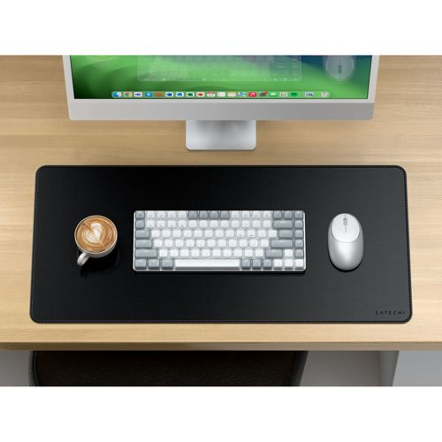 Een bureau met een monitor, toetsenbord, muis en een kop koffie.