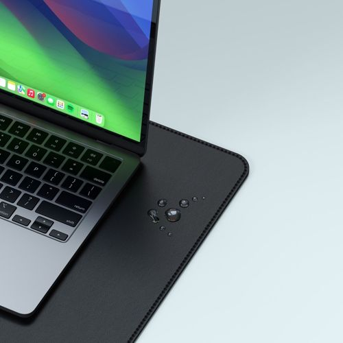 Een laptop op een zwarte bureauonderlegger met waterdruppels.