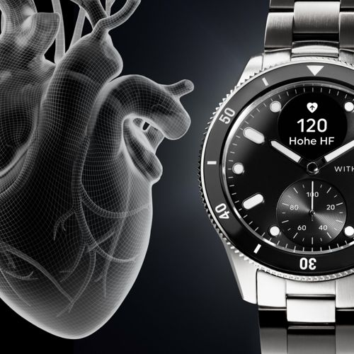 Drahtgitter-Herzmodell neben einer Smartwatch mit Herzfrequenzanzeige.