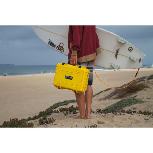 Person mit Surfbrett und gelber Tasche am Strand.