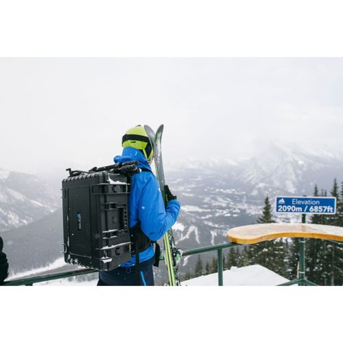 Ein Skifahrer mit Rucksack und Skiern steht auf einem schneebedeckten Aussichtspunkt.