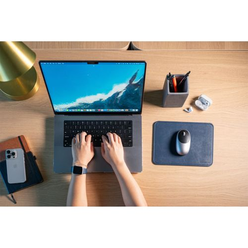 Hände tippen auf einem Laptop, daneben liegen Maus, Kopfhörer und Notizbuch.