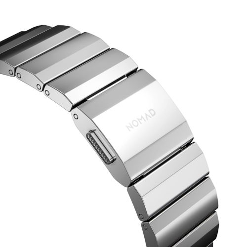 Primer plano de una correa de reloj de metal plateado con el logo de NOMAD en el cierre.