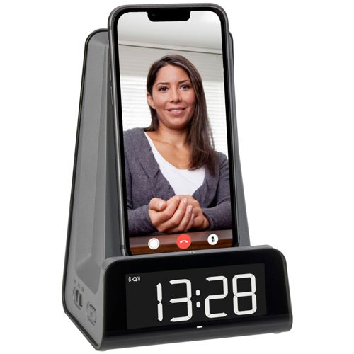 Eine Frau lächelt in einem Videoanruf auf einem Smartphone, das in einem Wecker steckt.
