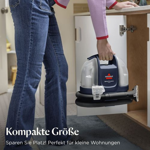 Una persona tiene un pulitore Bissell SpotClean blu e trasparente.