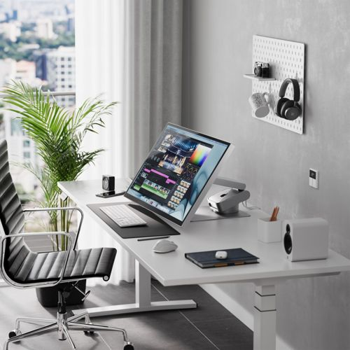 Ein aufgeräumter Schreibtisch mit einem Monitor, der eine Videobearbeitungssoftware anzeigt.