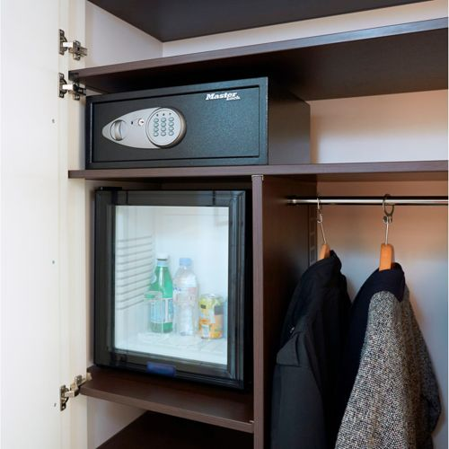 Armadio aperto con cassaforte, mini-frigo e vestiti su gruccia.
