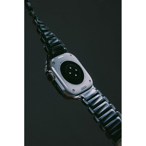 Rückseite einer Smartwatch mit schwarzem Armband auf dunklem Hintergrund.