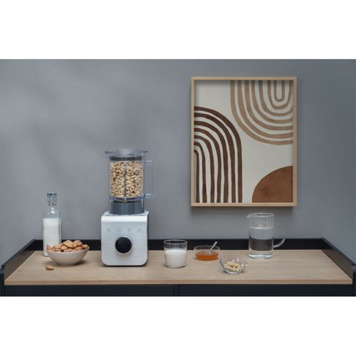 Ein Standmixer mit Nüssen, daneben Schüsseln mit Milch, Honig und Nüssen.