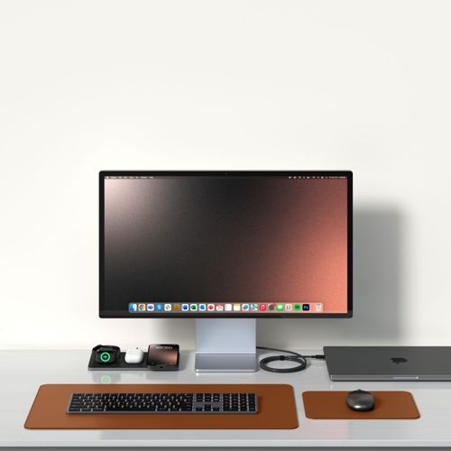 Ein Schreibtisch mit großem Monitor, Laptop, Tastatur, Maus und Ladestation.