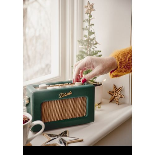 Radio Roberts verte sur rebord de fenêtre, main tournant bouton, déco Noël.