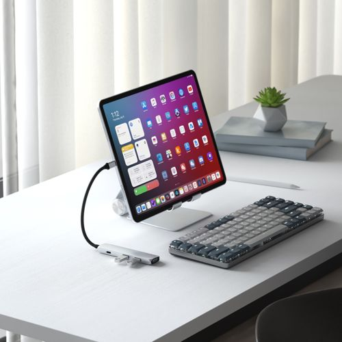 Ein Tablet mit Apps und Widgets steht auf einem Ständer neben einer Tastatur und einem USB-Hub.