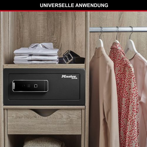 Una cassaforte nera Master Lock su uno scaffale in un armadio, con camicie piegate e cintura. Vestiti appesi a destra.