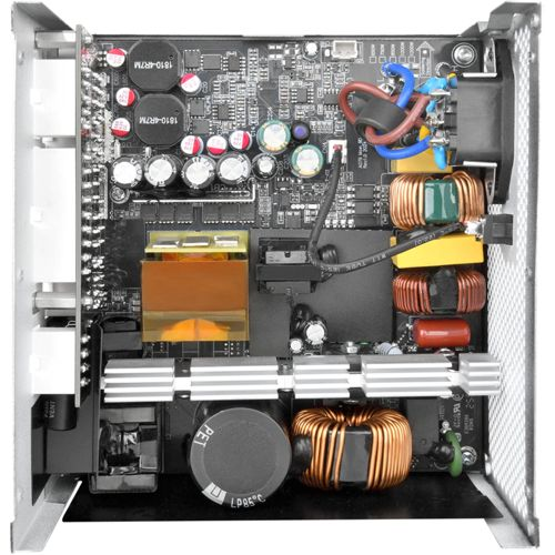 Vista interna di un alimentatore per computer con circuiti, condensatori, trasformatori e ventola.