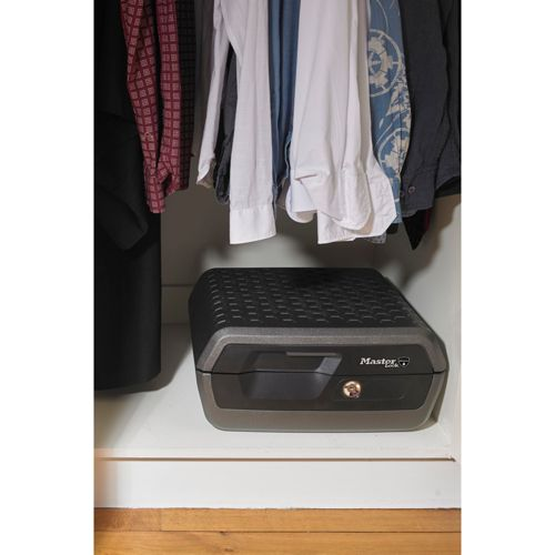 Una caja fuerte gris con cerradura está en un estante de un armario.