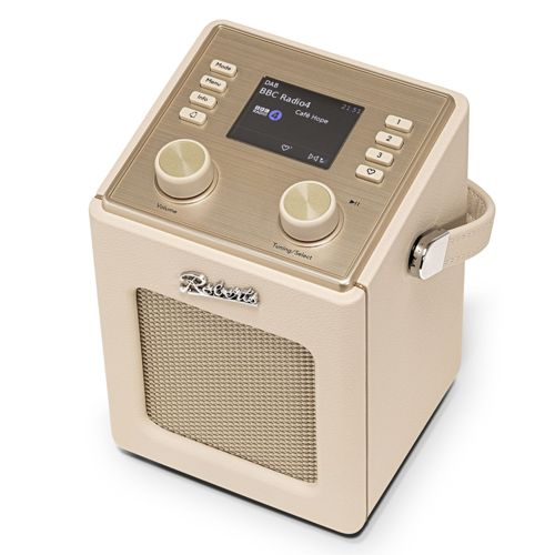 Une radio de couleur crème avec dessus, boutons et grille de haut-parleur dorés.