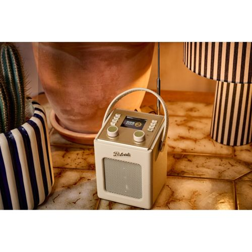 Une radio crème avec poignée est posée sur une table en marbre à côté d'une plante en pot.