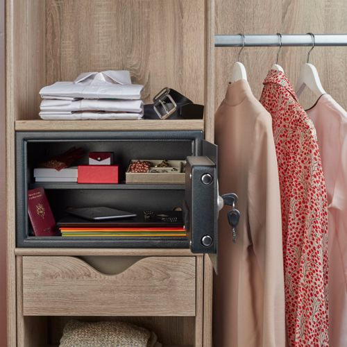 Puerta de caja fuerte abierta con ropa y documentos al lado. Ropa colgada a la derecha.