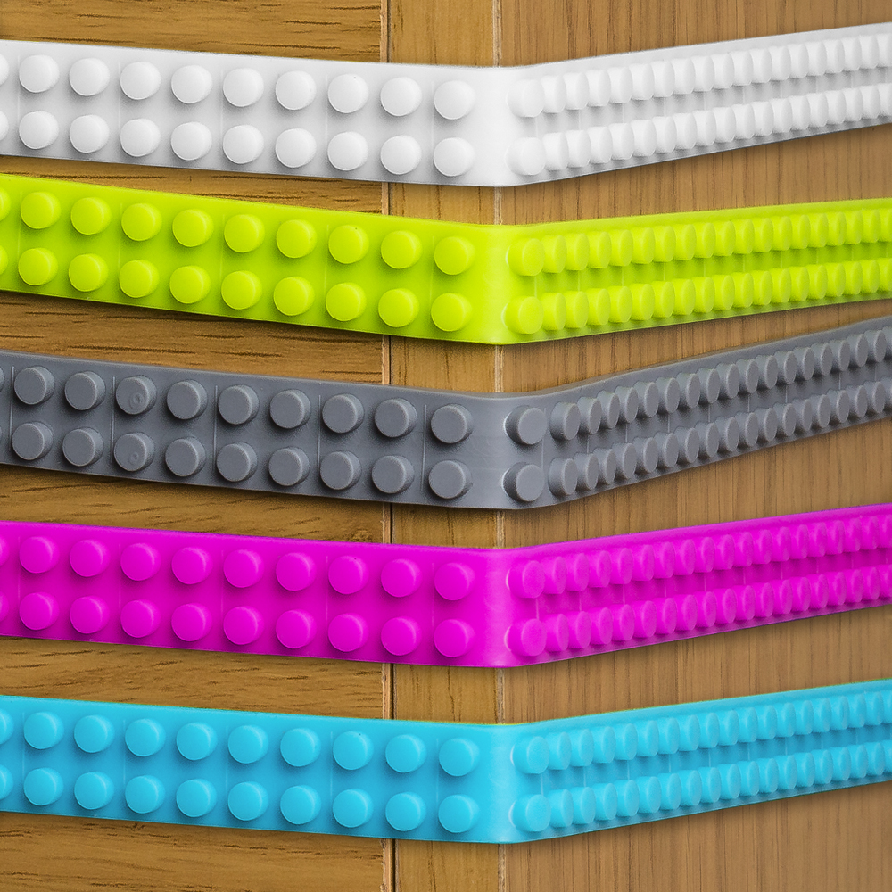 Cinque strisce colorate e flessibili con bottoni sono disposte diagonalmente su sfondo legno.
