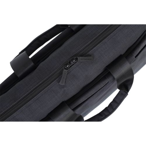 Close-up of a dark grey fabric bag with black zippers and handles. Zipper pull has text.