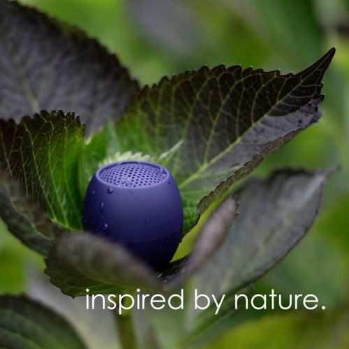 Een kleine paarse speaker rust op een blad, bedekt met waterdruppels.