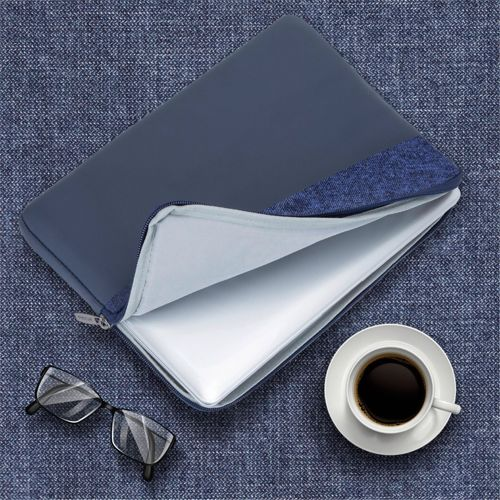 Una custodia blu scuro per laptop, aperta, con una tazza di caffè e occhiali nelle vicinanze.