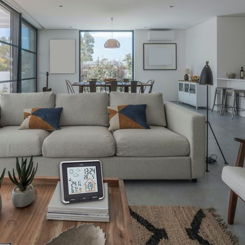 Ein modernes Wohnzimmer mit Sofa, Tisch und Wetterstation.