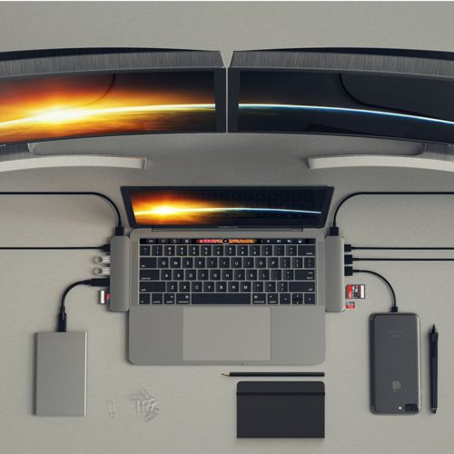 Un laptop con doppio monitor, hard disk esterno e telefono su una scrivania.