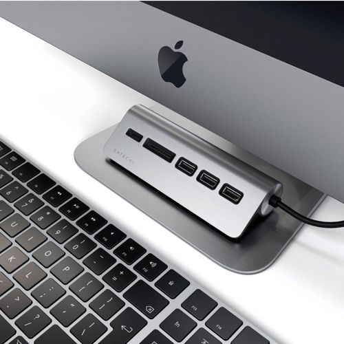 Un concentrador Satechi multiportos se encuentra frente a un iMac y un teclado.