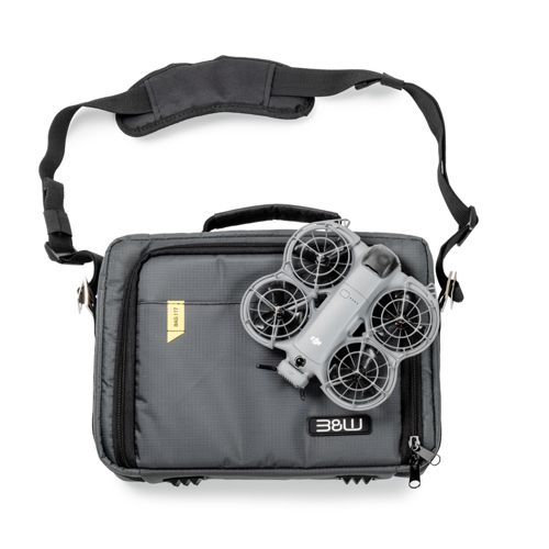Borsa grigia con un piccolo drone quadricottero appoggiato sopra. Sfondo bianco.